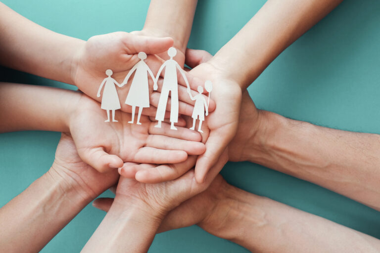 hands holding paper family cutout, family home,adoption foster care, homeless charity, family mental health, homeschooling , household budget during recession concept