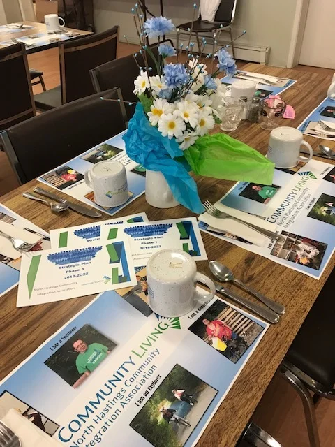 Place settings and NHCIA Community Living materials displayed at a community lunch.
