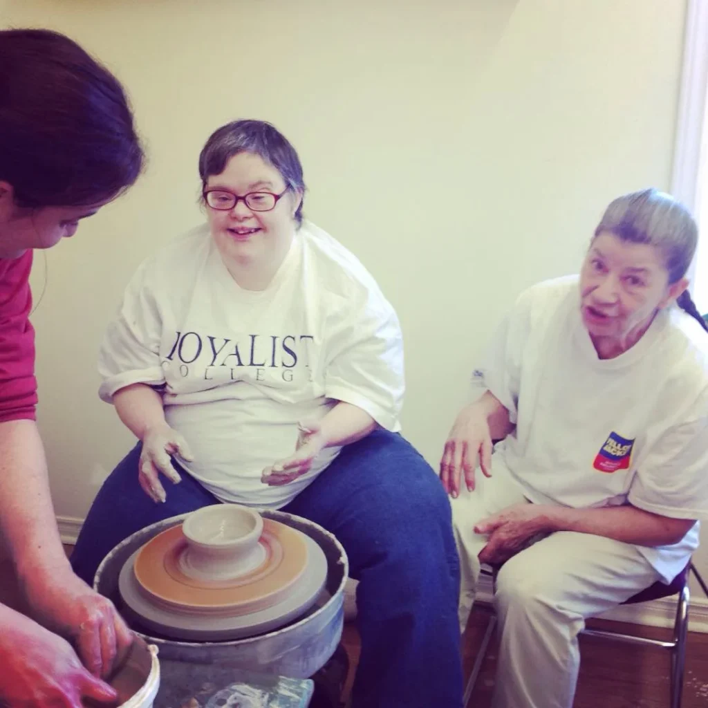 Group learning pottery techniques together, including wheel work and hand building, at a Kairos Time session.