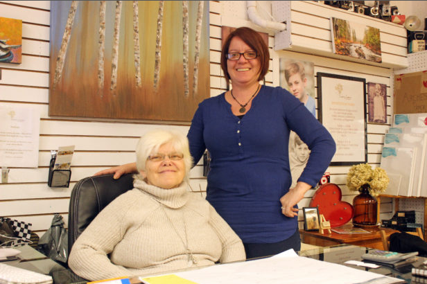 Karen Keller and a supporter stand together in a gallery space displaying her photography work.